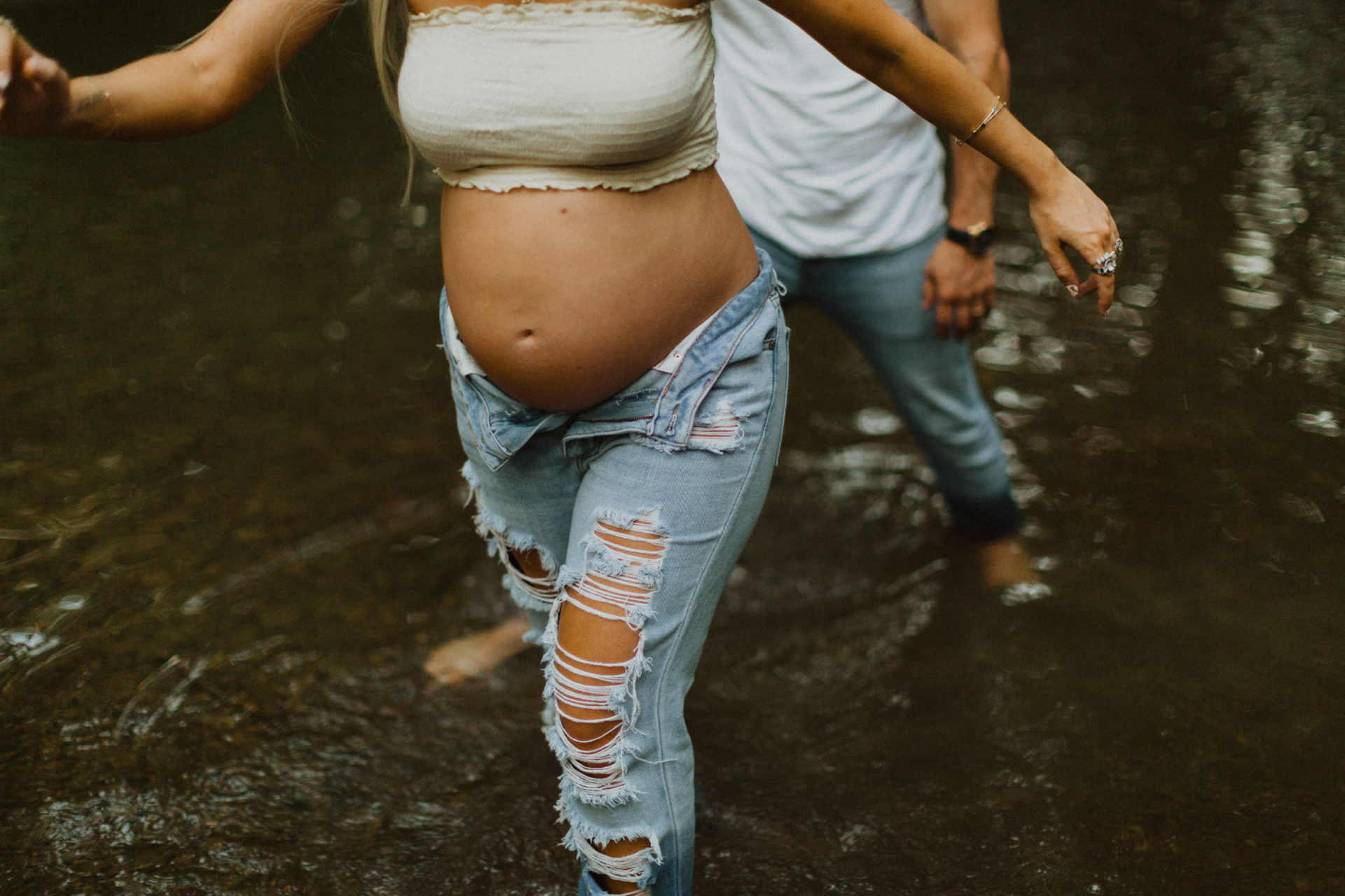 his and hers playful maternity shoot in a creek