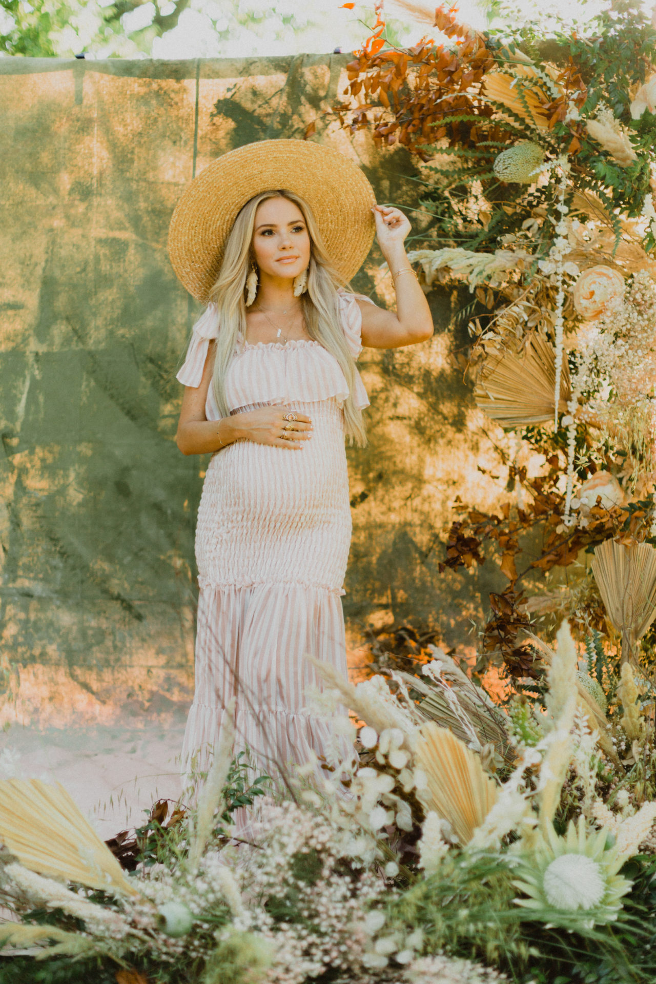 glowing maternity shoot with wild flowers and sun hat