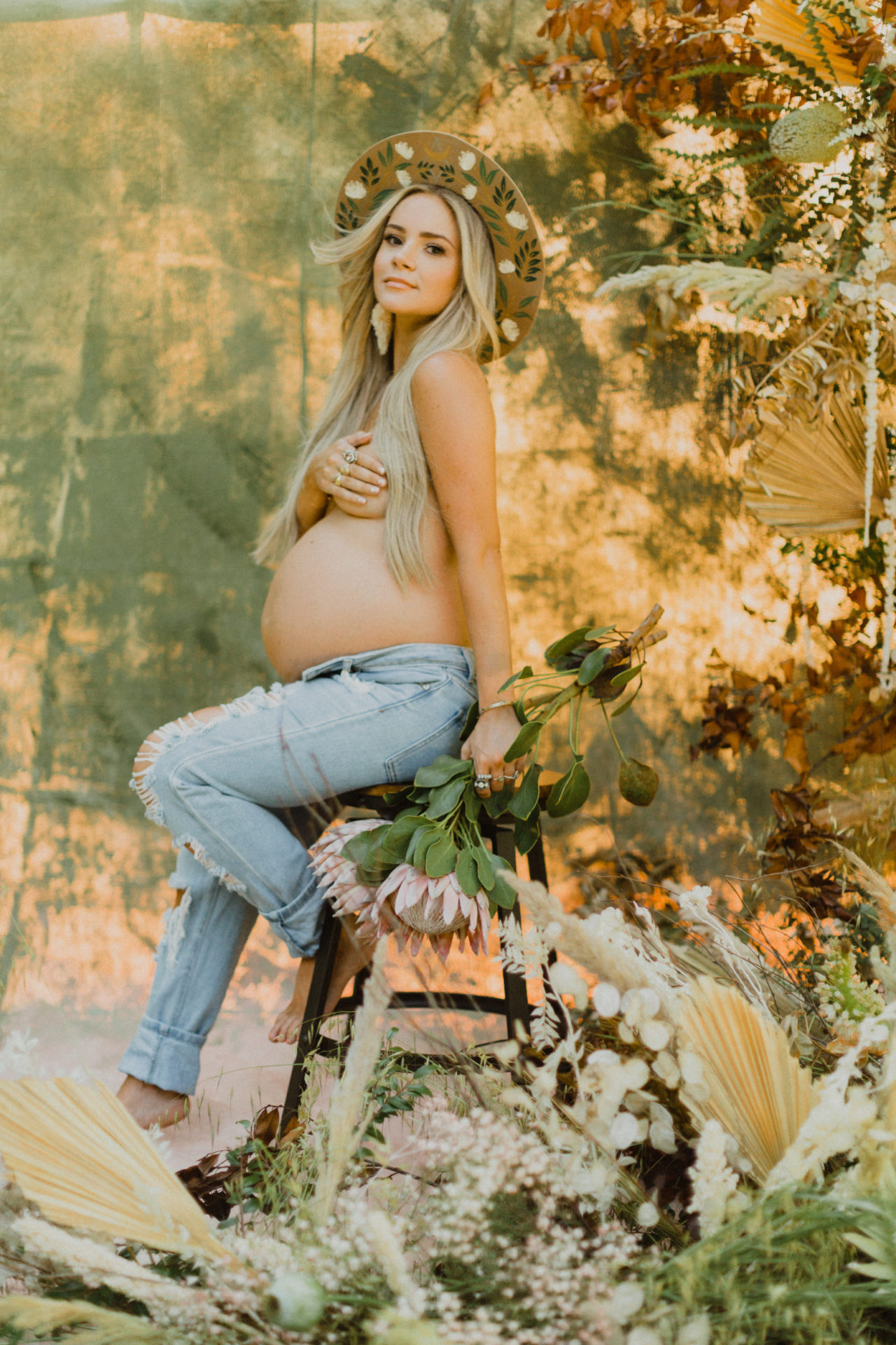 natural outdoor maternity shoot with wildflowers and painted hat