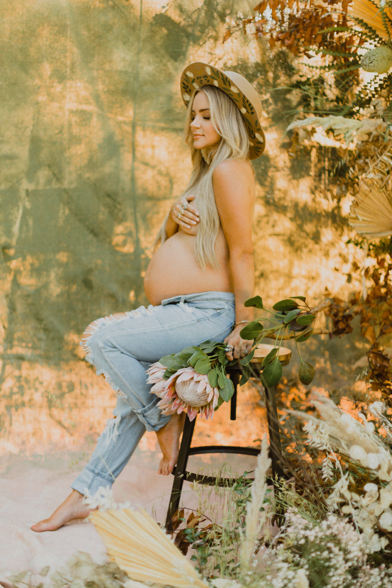 natural outdoor maternity shoot with wildflowers and painted hat